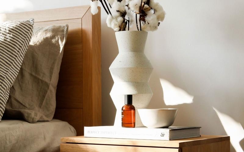 a vase with cotton stems on a bedside table