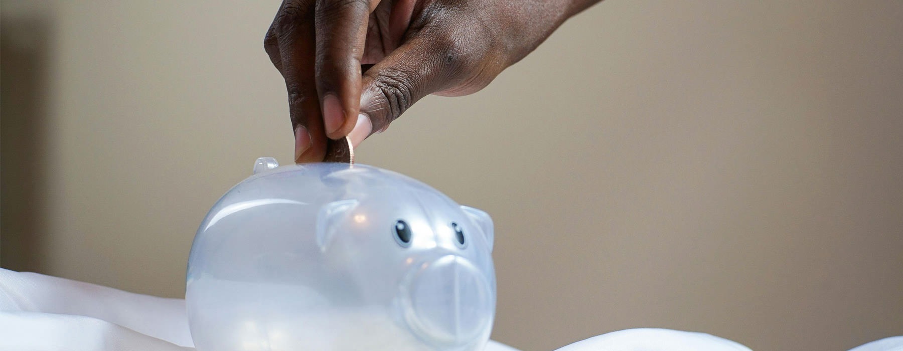 man putting coin in piggy bank